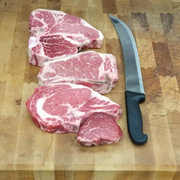 knife and raw steak on butcher block