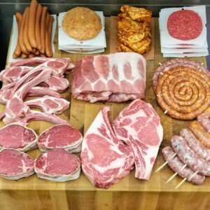 selection of raw beef cuts, sausages, and patties