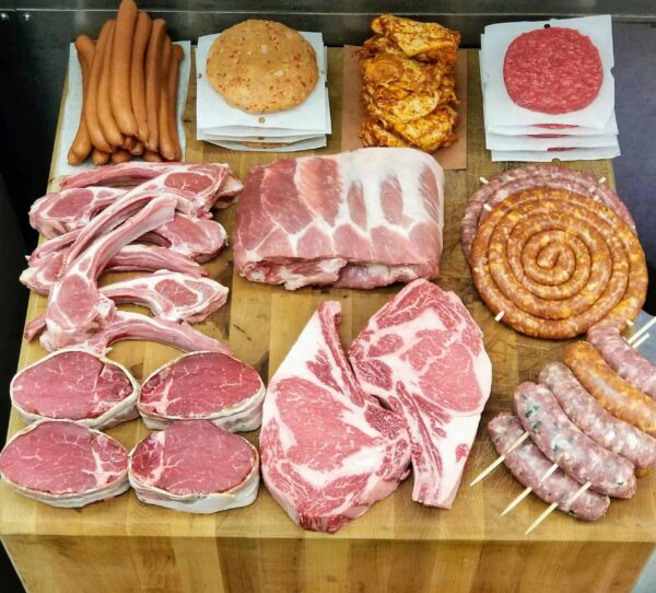 selection of raw beef cuts, sausages, and patties